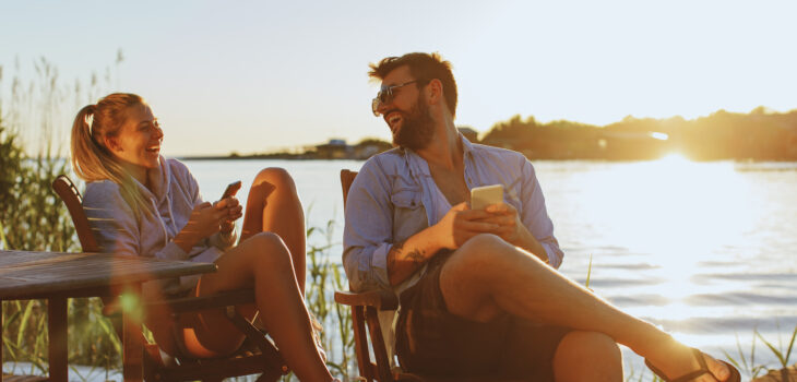 Young woman and man using smartphone by the river
